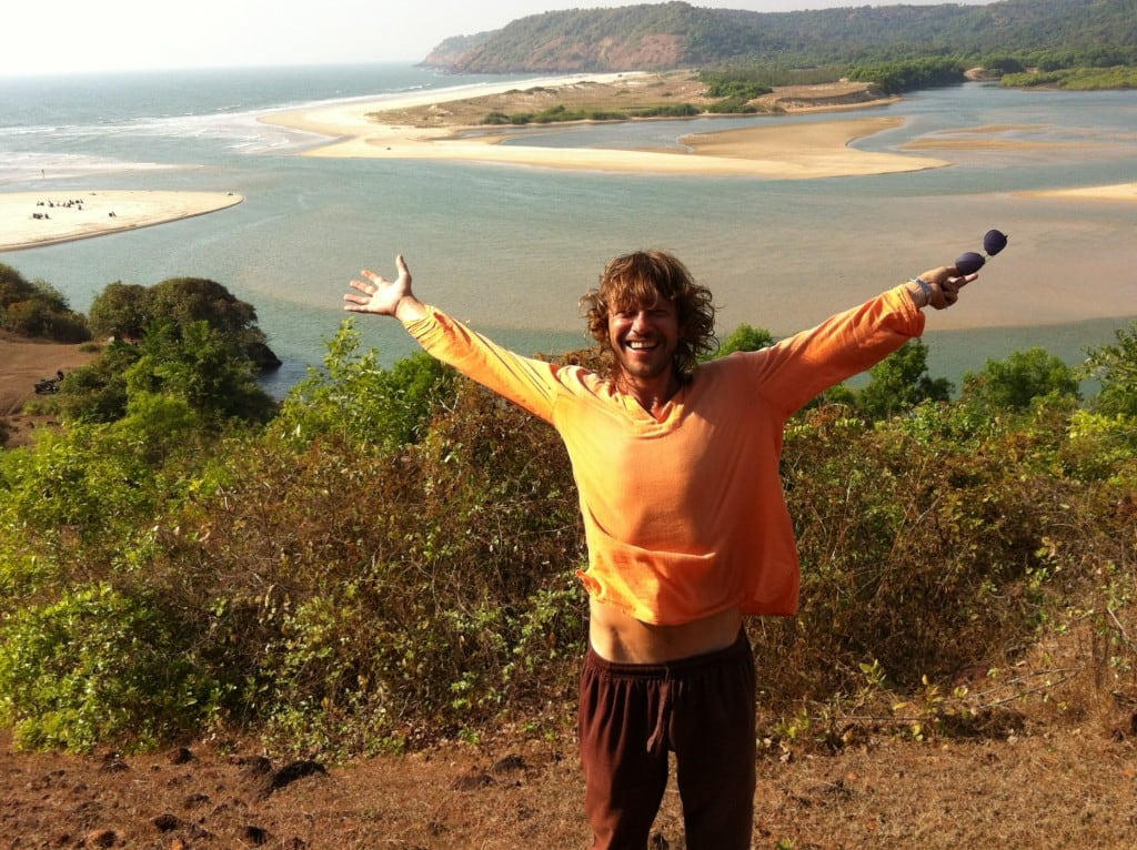 Eugene Lukyanenko with his arms open above a coastal landscape in Maharashtra, India, in 2021.